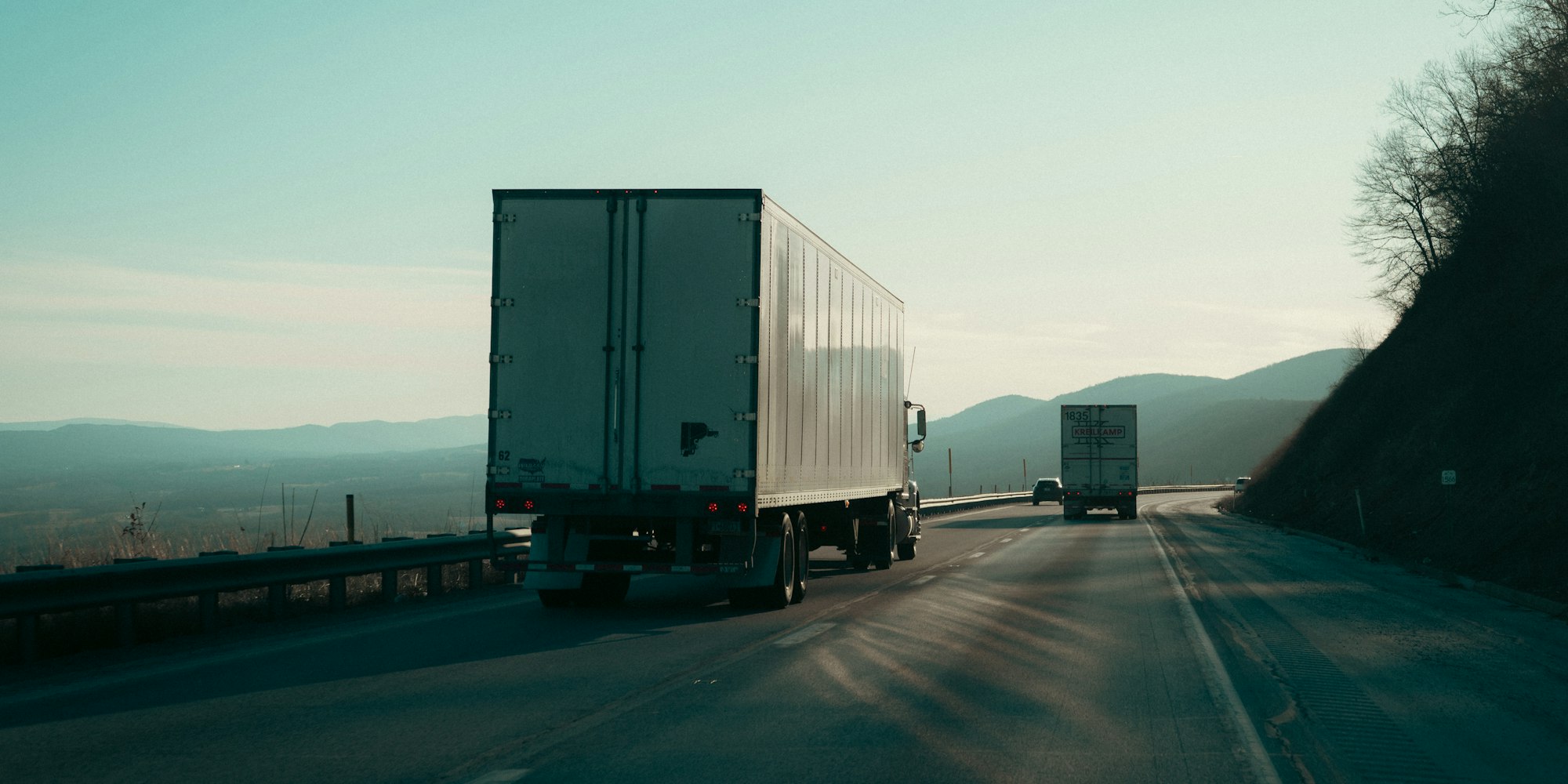 Semi truck pulling a white trailer along a highway