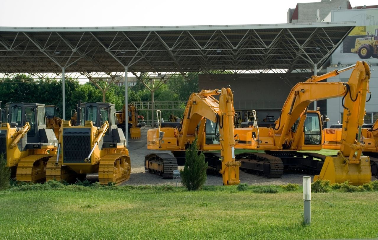 Yellow construction excavators and bulldozers parked under a covered depot for asset and equipment tracking.
